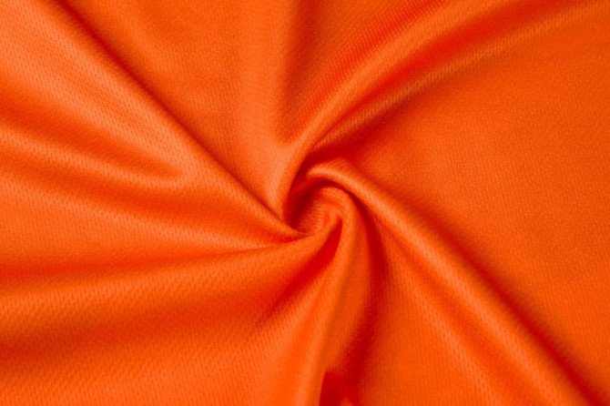 An orange fabric with a smooth texture, displayed in a swirling pattern. Features a subtle sheen.