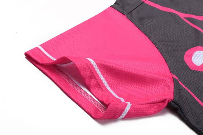 A close-up of a sports top featuring grey and bright pink fabric with a curved hem and stitched edges.