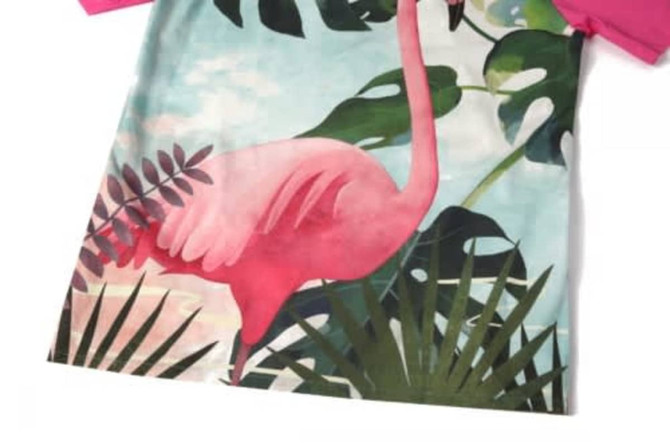 A vibrant beach shirt featuring a pink flamingo design and green tropical foliage. Short-sleeved with a colourful pattern.
