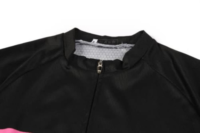 A black sports jersey with a zip collar and pink design elements, featuring a logo on the fabric.