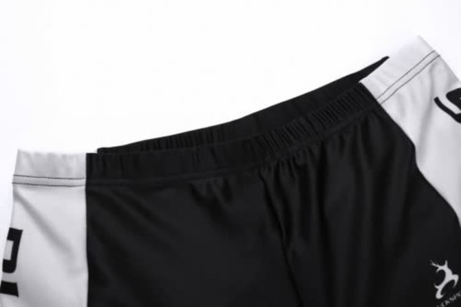 A pair of black and white sports shorts featuring an elastic waistband and a logo on the side.