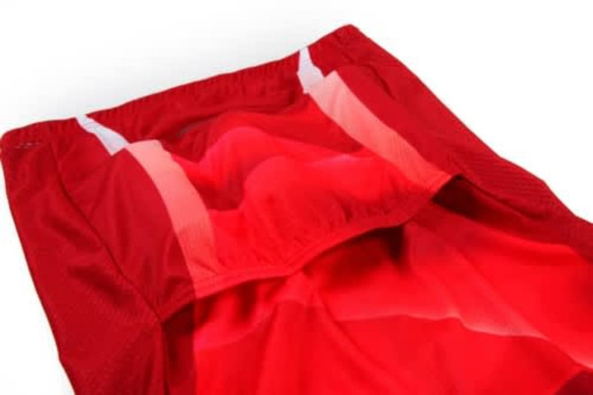 A red cycling uniform featuring breathable fabric with white accents and a logo. The interior showcases a smooth finish.