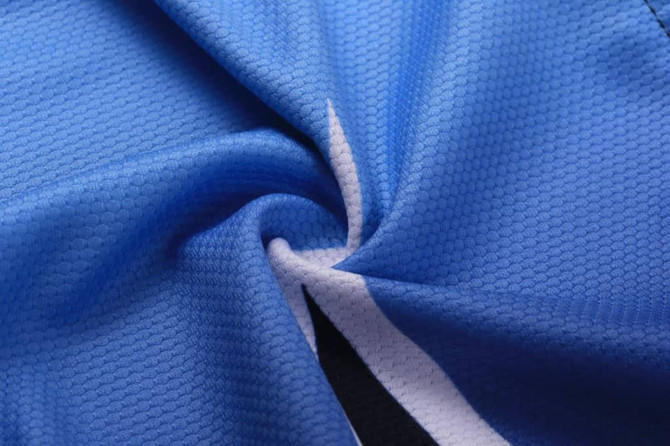 A close-up of a blue sublimated cycling team wear tee, featuring textured fabric and a logo.