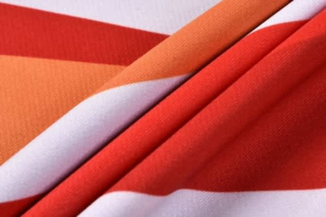 A vibrant AFL player uniform in red, orange, and white, featuring a fabric design with diagonal stripes.