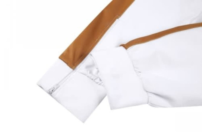 A cricket uniform featuring a white design with a brown accent. The image displays a close-up of the sleeve and zip.