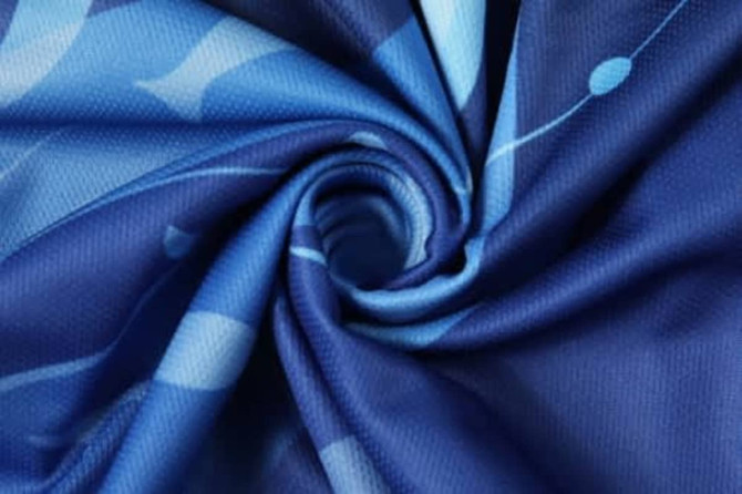 A blue fabric with a swirl pattern featuring varying shades of blue, designed for sports uniforms.