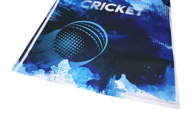 A blue cricket jersey featuring a graphic design and a logo. The fabric appears lightweight and breathable.