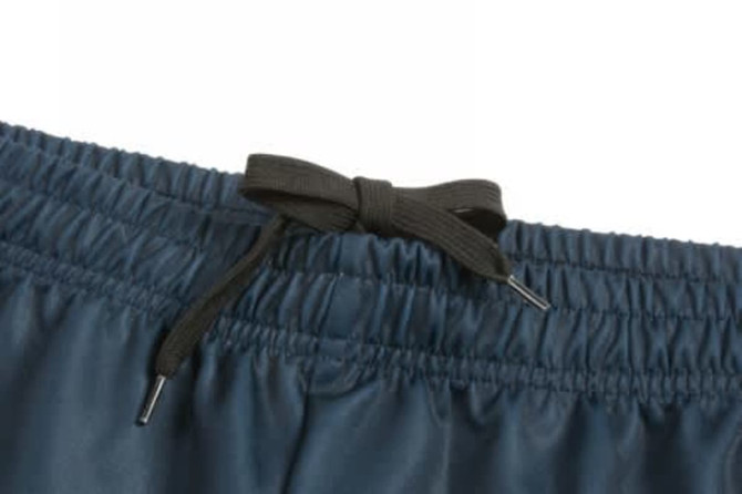 A close-up of dark navy shorts featuring an elastic waistband with a black drawstring. There is a logo on the waistband.