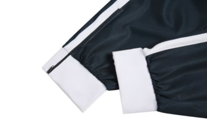 A dark green cricket jersey sleeve featuring white cuffs and a zipper detail. The jersey has a branded logo.