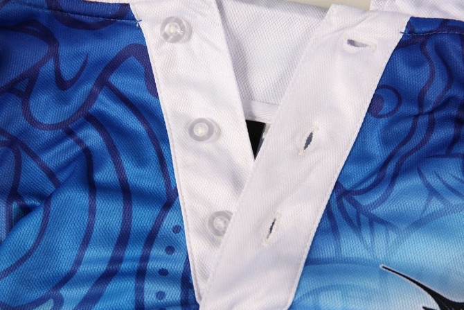 A blue and white sports uniform featuring a buttoned neckline and a vibrant design, with a logo present.