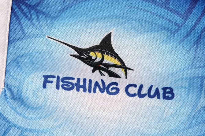 A blue sports jersey featuring a fishing club logo with a stylised fish design.