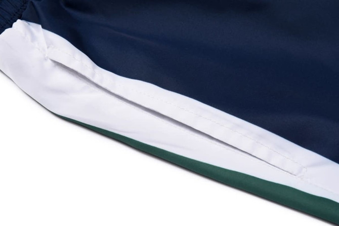 A close-up view of a navy blue sports uniform with white and green accents, featuring a logo on the side.