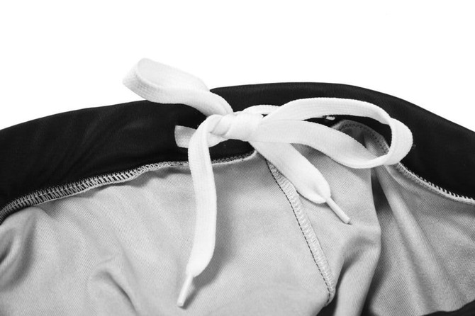 A close-up of a black and grey sports uniform with a white tie at the waist, featuring a branded logo.