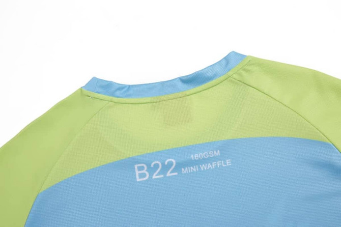 A sailing club t-shirt in green and blue with a branding logo on the back.