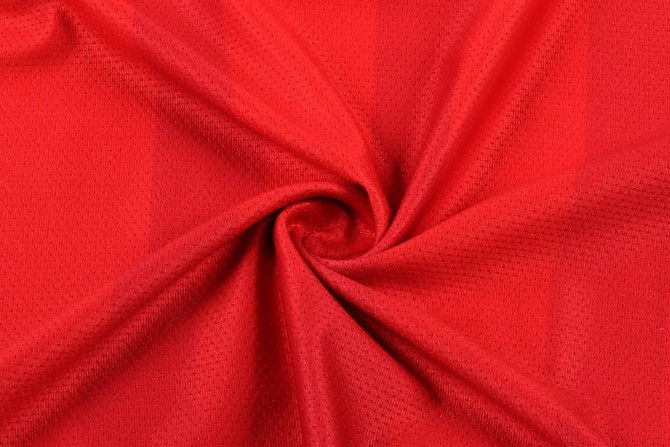 A red fabric featuring a textured pattern, suitable for a women's soccer uniform tee. Contains a logo.