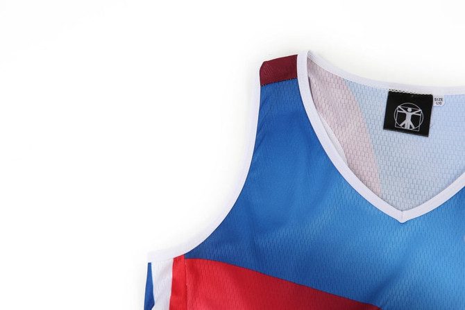 A netball dress featuring blue, red, and white colours, with a mesh design and branding on the tag.