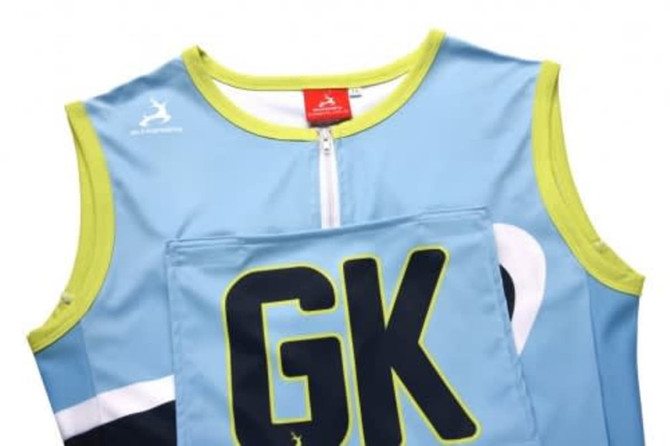 A blue netball bib with green accents and a large "GK" printed on the front. It features a logo.