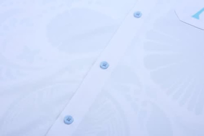 A white school wear shirt featuring light blue buttons and a subtle pattern. It includes a logo.