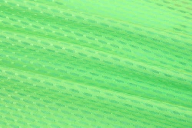 A close-up of vibrant green fabric, featuring a textured pattern, ideal for race staff bibs.