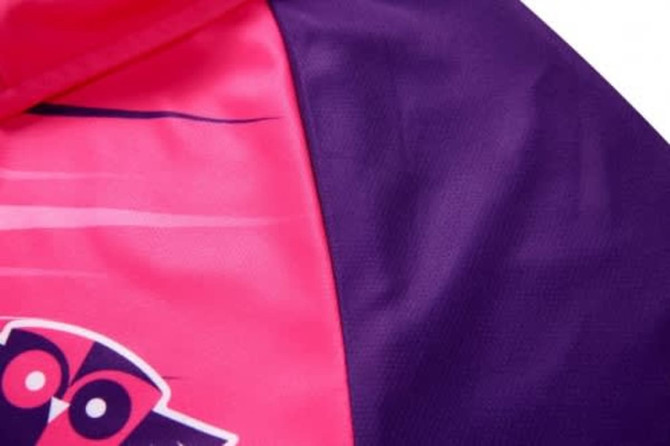 A close-up of a sports uniform featuring vibrant pink and purple sections, with a logo present on the garment.