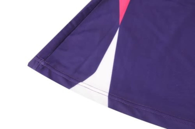 A purple sports uniform with geometric patterns in pink and white, featuring a stitched hem and vibrant design.