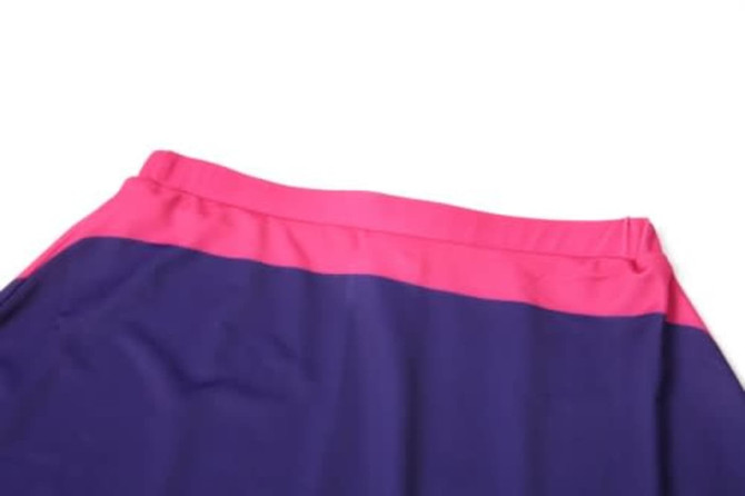 A sports uniform featuring a combination of purple and pink fabric, with an elastic waistband and a branded logo.