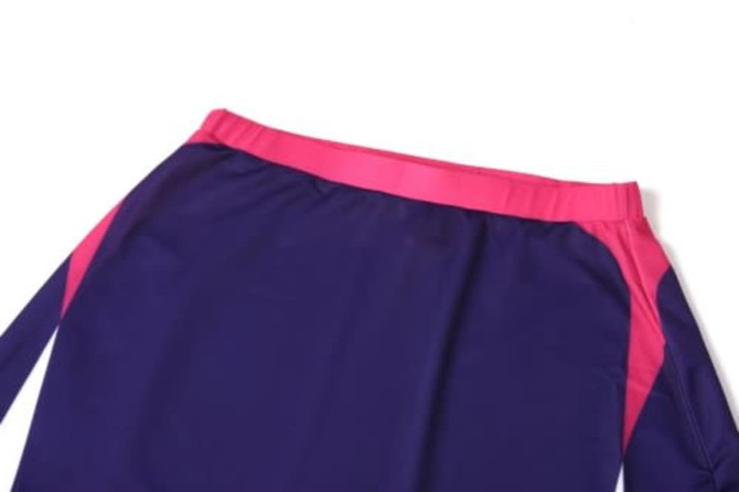 A purple sports uniform with a pink waistband and side accents, featuring a logo.