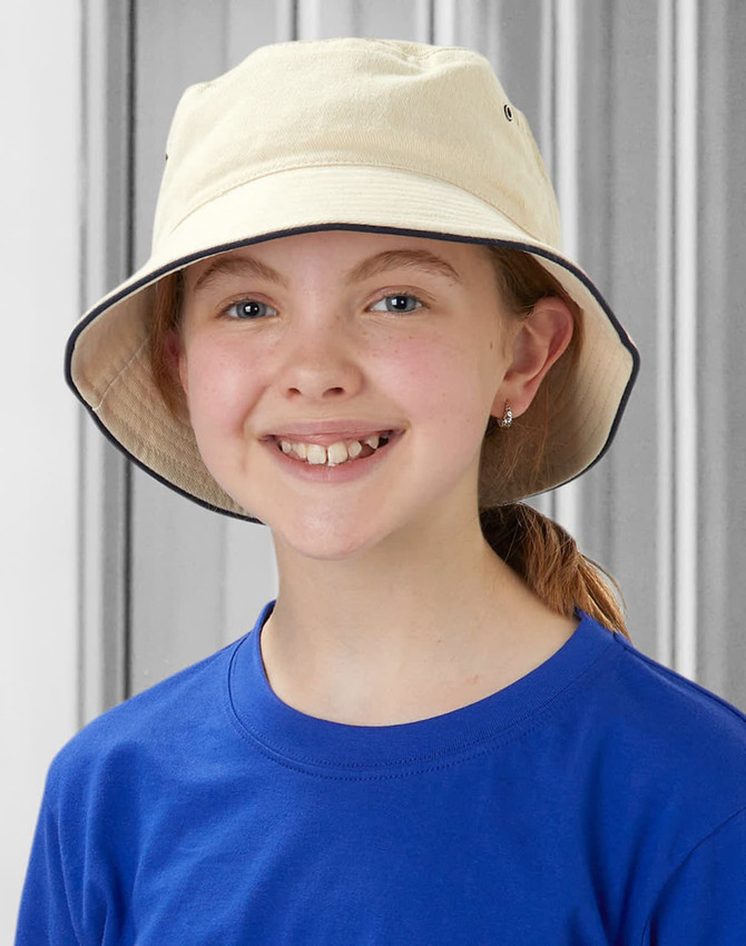 A child wearing a soft washed cream bucket hat with a contrasting trim, set against a grey background.
