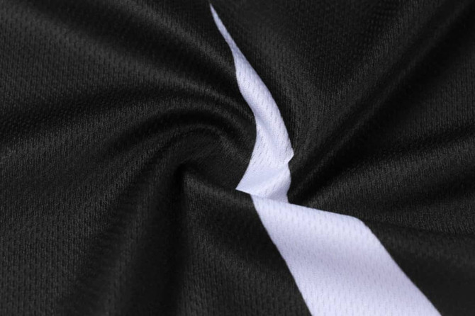 A close-up of black basketball shorts with a white stripe and textured fabric. The item features a logo.