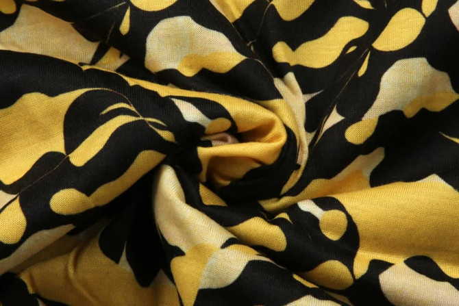 A fabric featuring a black and yellow abstract pattern, showcasing a swirl design.