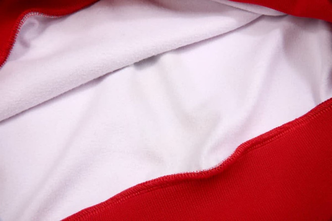 A red pullover hoodie with a white fleece interior and a logo or branding on the outside.