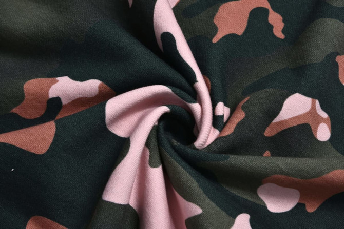 A close-up view of twisted fabric featuring a camouflage pattern in green, pink, and brown hues.