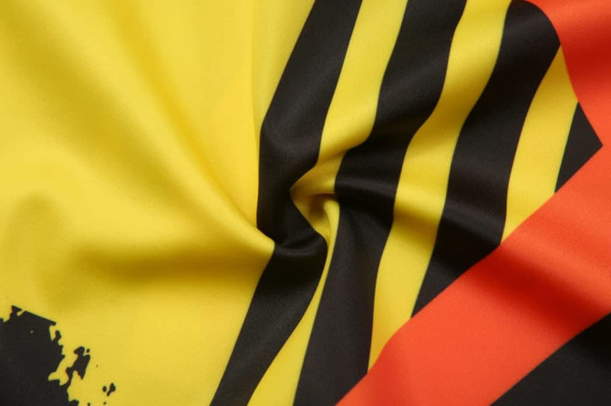 A close-up of fabric featuring bold yellow, black, and red stripes with a smooth texture.