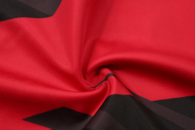 A close-up of red and black fabric with a smooth, swirling texture, featuring abstract patterns.