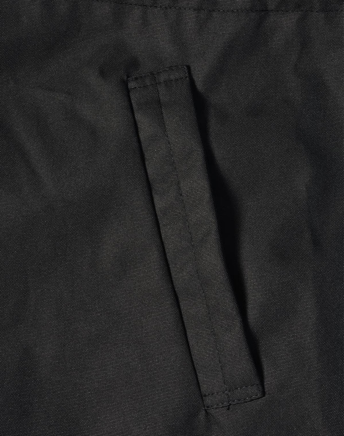 A close-up of a black fabric featuring a stitched pocket on a jacket. The material appears durable and textured.