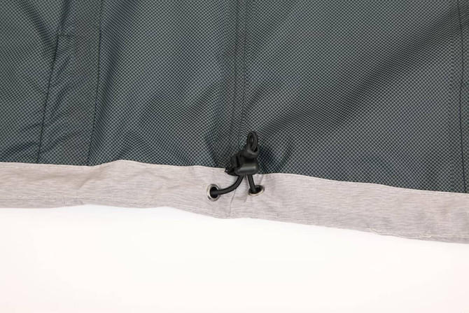 A grey and dark green waterproof performance jacket, featuring a hook detail at the hem. It has a logo.