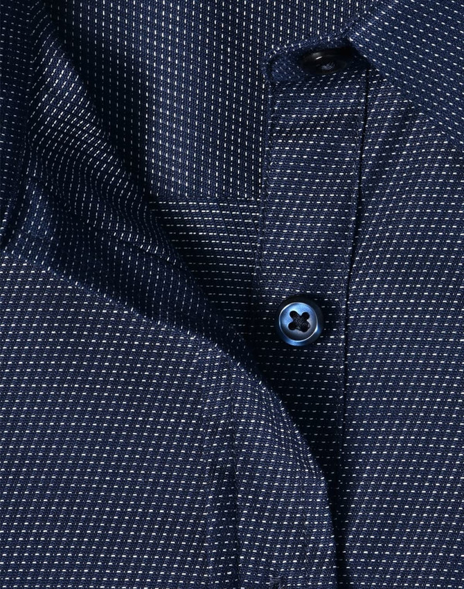 A navy blue ladies' button-up shirt with a pin dot pattern and a blue button. Features a classic collar design.