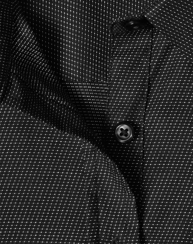 A close-up of a black ladies' button-up shirt with a pin dot pattern and a visible button.