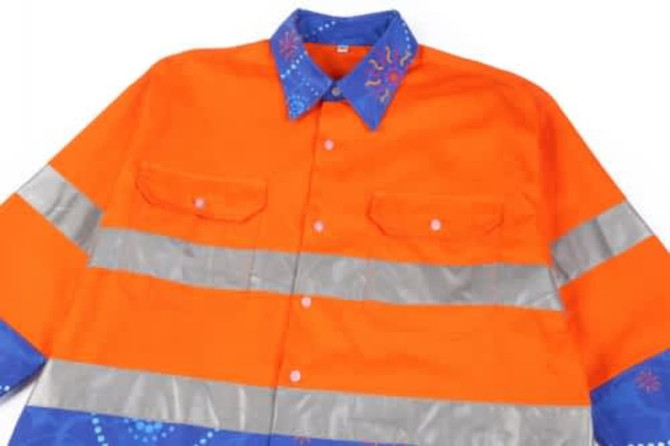 A vibrant orange Hawaiian shirt with reflective silver stripes and a blue patterned collar, featuring a logo.