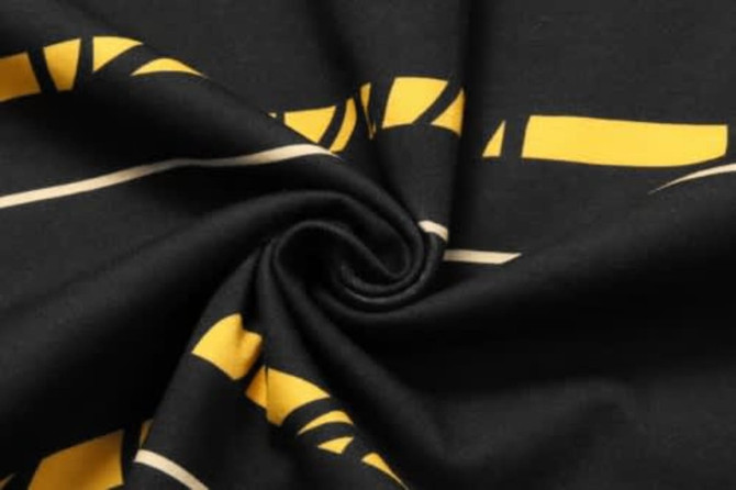 Cotton fabric featuring a black background with yellow and beige graphic patterns.