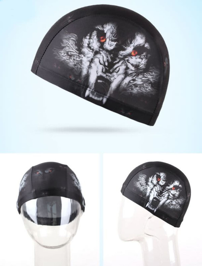 A black swimming cap featuring a graphic design of a fierce face with red eyes. It has a logo on it.