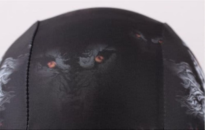 A black swimming cap featuring a graphic design with fierce eyes and a textured pattern. It has a logo.