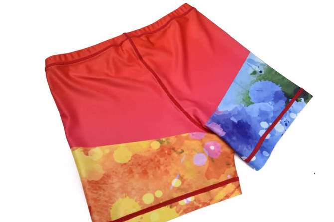 Bright red and multicoloured shorts featuring a vibrant abstract design, with a logo on the waistband.