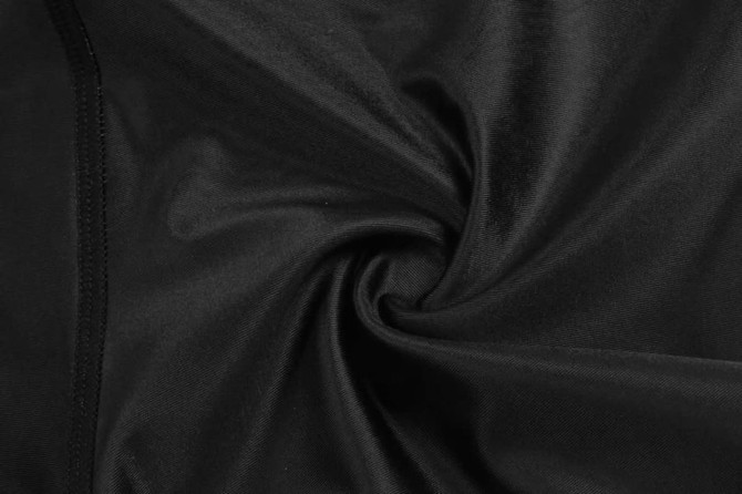 A close-up of smooth, black fabric, showcasing a swirling texture. The material appears soft and sleek.