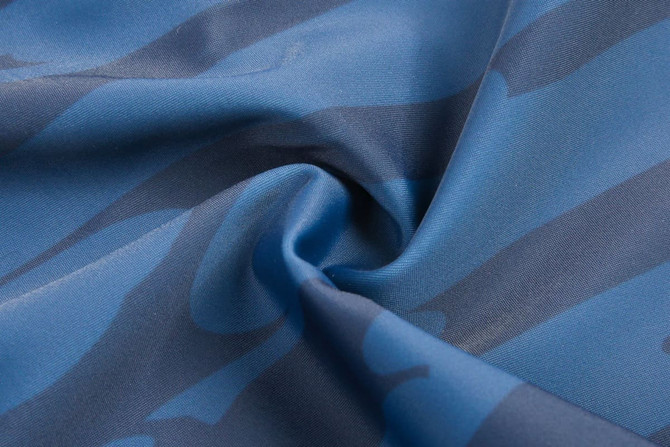 A fabric in shades of blue featuring a wavy camouflage pattern, with a smooth texture.