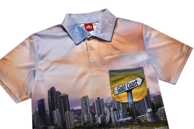 A polo shirt featuring a vibrant landscape design of the Gold Coast skyline with a pocket. The shirt has a light blue collar.