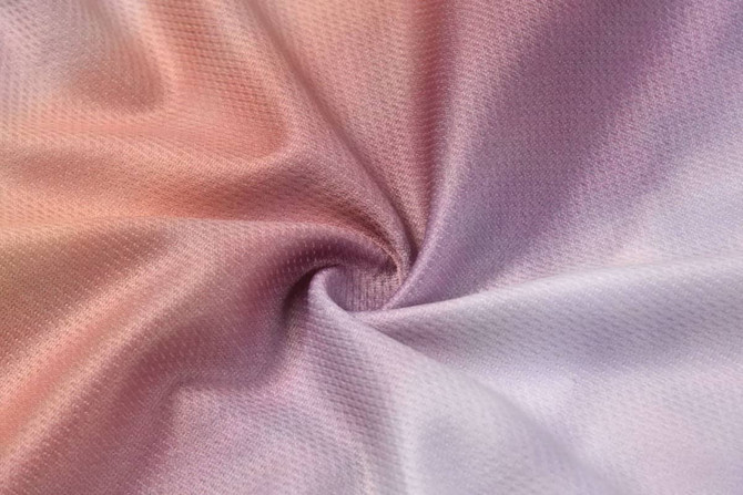 A textured fabric in shades of soft pink, purple, and white, featuring a smooth, swirling pattern.