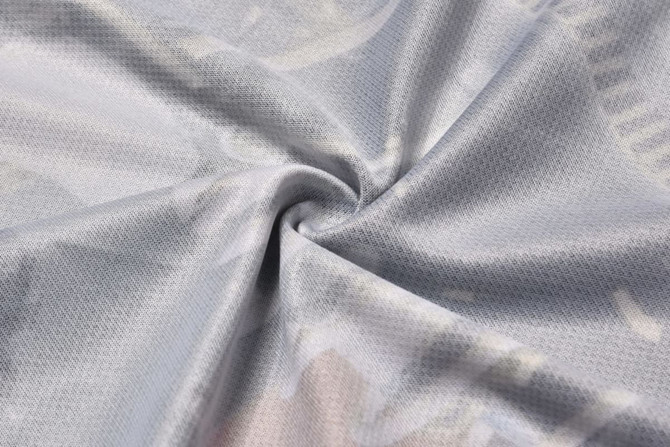 A close-up of light grey fabric with a smooth texture, featuring a subtle, patterned design and a logo.