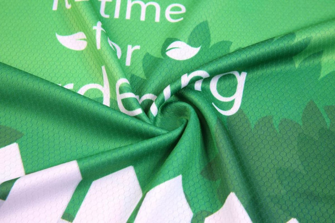 A green fabric featuring a hexagonal pattern, with text and leaves in a spiral arrangement. It has a logo.