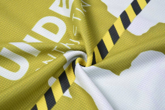 A patterned fabric featuring yellow and black stripes, with an abstract design. It has a logo present.